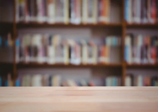 Дерев'яний стіл проти розмитої книжкової полиці — стокове фото