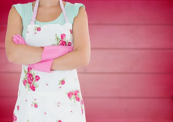 腕を組んでぼやけたピンク木製パネルに対して花のエプロンの女性 — ストック写真