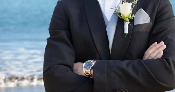 Groom seção meio com os braços dobrados contra a praia borrada — Fotografia de Stock