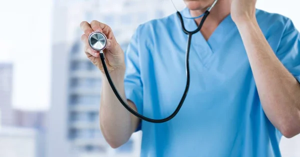 Pielęgniarka z stetoskop połowie sekcji przeciw budynkom rozmazane — Zdjęcie stockowe