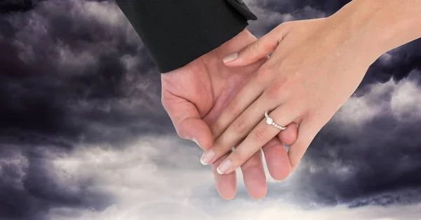 暗い雲の前で手を繋いでいる結婚式のカップル — ストック写真