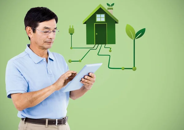 Man met Tablet PC- en groene huis afbeelding tegen groene achtergrond — Stockfoto