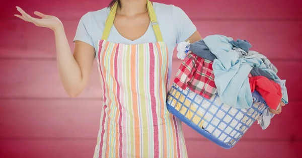 Woman in apron with laundry against blurry pink wood panel — Stock Photo, Image