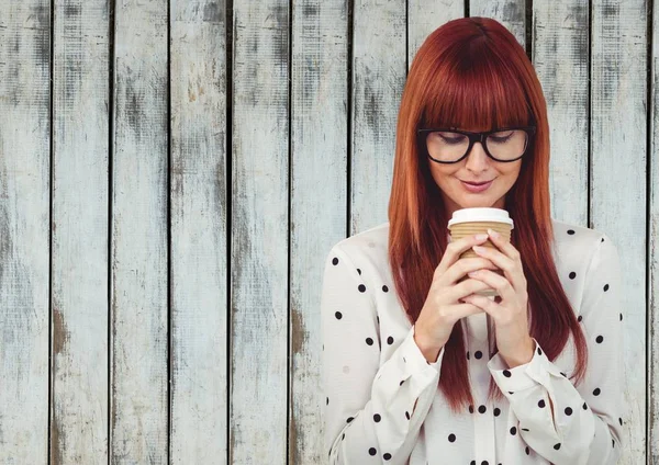 Kvinna som tittar på kaffekopp mot träpanel — Stockfoto