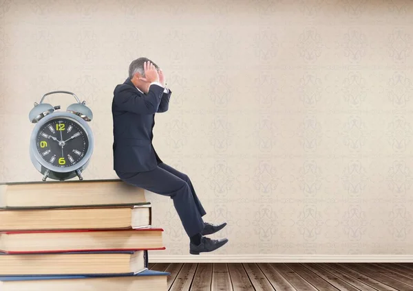 Hombre de negocios estresado sentado en libros apilados en el estante con reloj — Foto de Stock