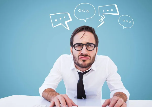 Man at desk with white speech bubbles against blue background — Stock Photo, Image