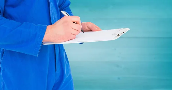 Mecânico com prancheta contra painel de madeira azul embaçado — Fotografia de Stock