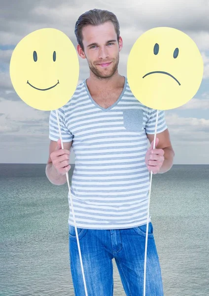 Man holding happy and sad faces against sea — Stock Photo, Image