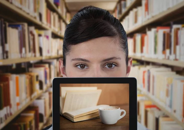 Kobieta z tabletki przedstawiającej książki i kawa stosunku blurry regały — Zdjęcie stockowe