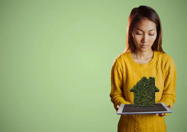 Vrouw kijken neer op de Tablet PC- en struik huis tegen een groene achtergrond — Stockfoto