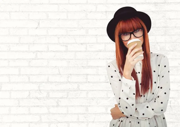 Woman in polka dot shirt with coffee cup over face against white brick wall — Stock Photo, Image