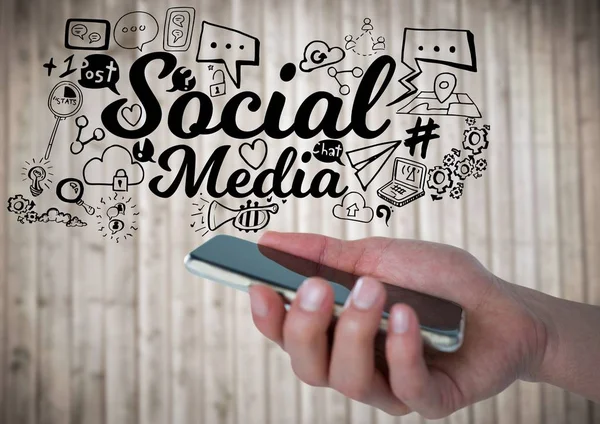 Ręka z telefonu i czarny social media doodles stosunku blurry panelu wood — Zdjęcie stockowe