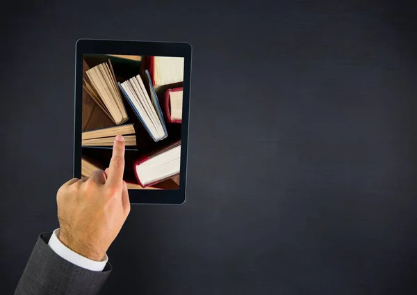 Hand touching tablet showing standing books on navy table — Stock Photo, Image
