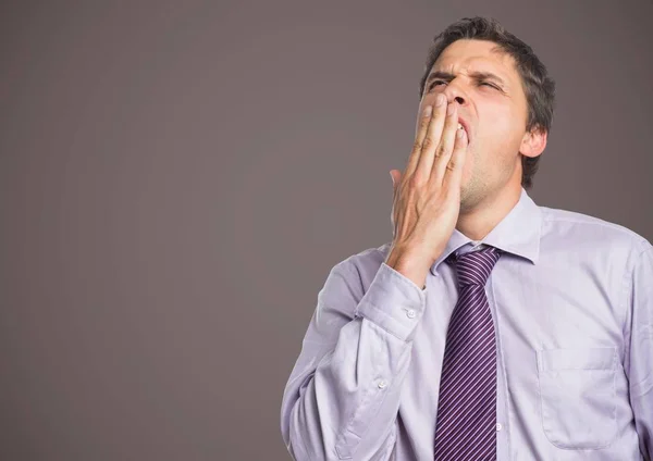 Man in lavendel shirt geeuwen tegen bruin grijze achtergrond — Stockfoto