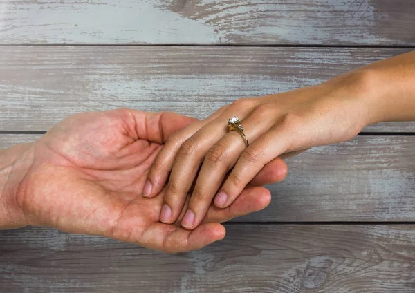 Boda pareja comprometida cogida de la mano contra madera —  Fotos de Stock