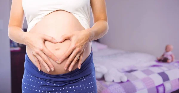 Zwangere vrouw midden sectie waardoor hart vorm — Stockfoto