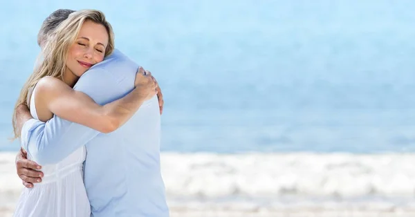 Casal abraço contra praia embaçada — Fotografia de Stock