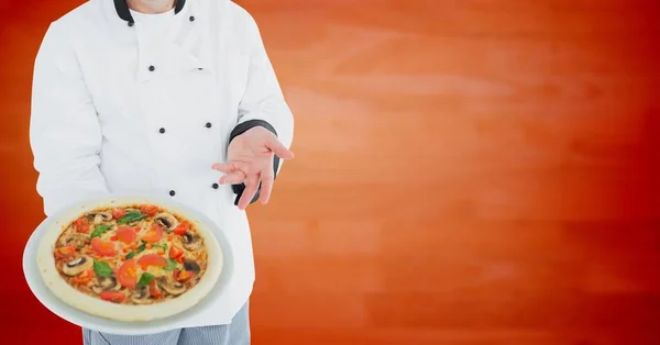 Chef con pizza contra panel de madera naranja borrosa —  Fotos de Stock