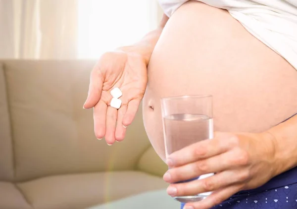 Gravid kvinna mitten av avsnittet med medicinering i suddiga vardagsrum — Stockfoto