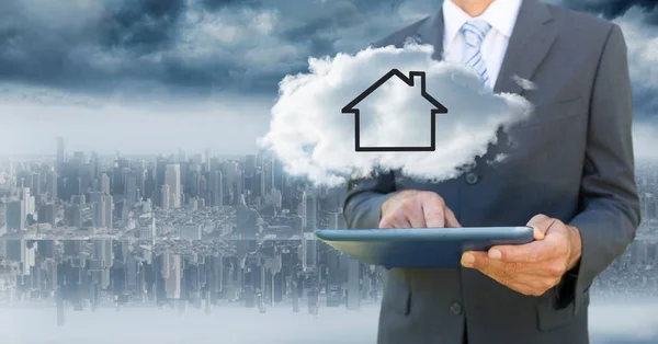Business man with tablet and cloud with house against blurry skyline — Stock Photo, Image