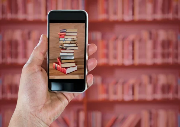 Mão com telefone mostrando pilha livro contra estante borrada com sobreposição vermelha — Fotografia de Stock