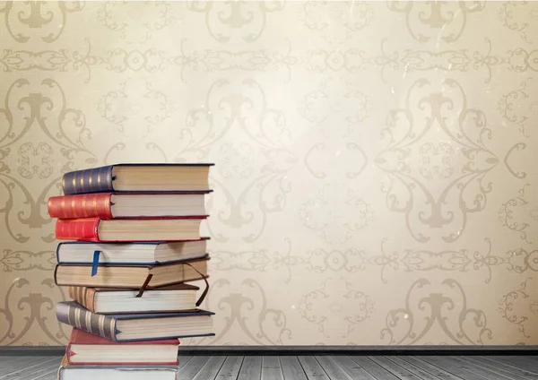 Books stacked by decorative wallpaper antique