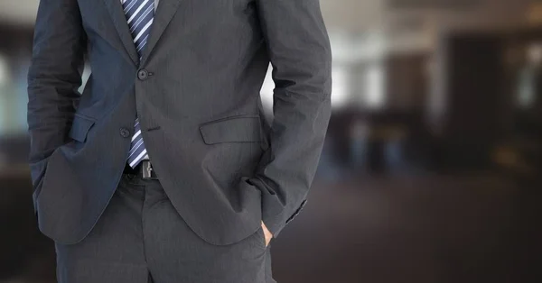 Obchodní muž s kontrastním ruce v kapsách v rozmazaný místnosti — Stock fotografie