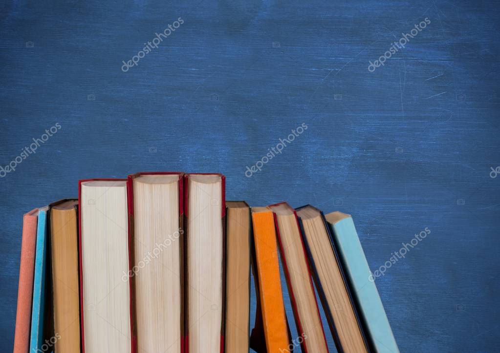 Digital composite of Standing books against blue chalkboard