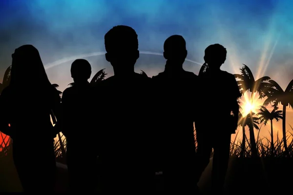 Silhouetten van groep staande tegen zonsondergang met palmbomen — Stockfoto