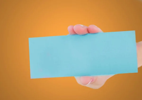 Mano que sostiene la tarjeta azul en blanco contra fondo naranja —  Fotos de Stock