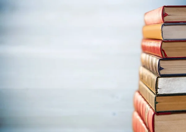 Mucchio di libri contro pannello di legno grigio sfocato — Foto Stock