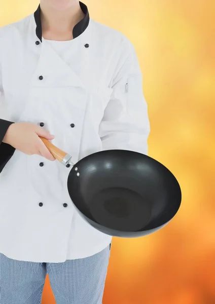 Chef-kok met wok tegen wazig gele achtergrond — Stockfoto