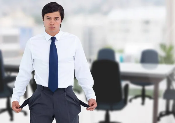 Trauriger Geschäftsmann mit leeren Taschen vor Bürohintergrund — Stockfoto