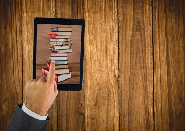 Hand touching tablet showing book pile on table — Stock Photo, Image