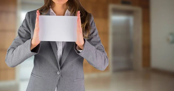 Mujer de negocios sección media con tarjeta en blanco contra ascensores borrosos — Foto de Stock