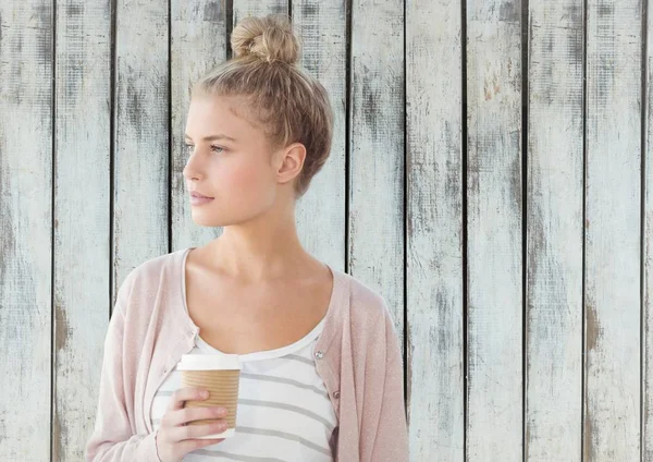 Woman looking to side holding coffee cup against wood panel — Stock Photo, Image