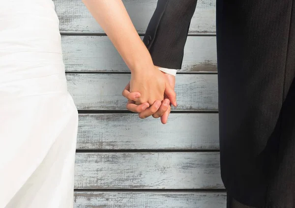 Wedding couple holding hands against wood — Stock Photo, Image