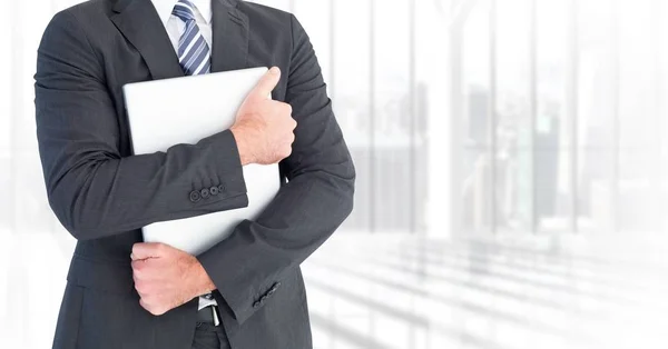 Hombre de negocios sección media celebración de ordenador portátil contra ventana borrosa — Foto de Stock