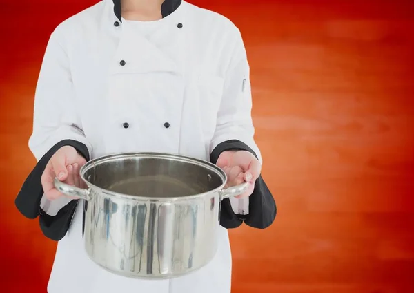 Chef avec casserole contre panneau de bois orange flou — Photo