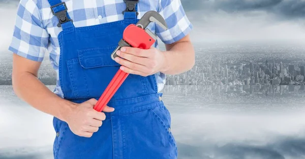 Handyman with red wrench against blurry skyline — Stock Photo, Image