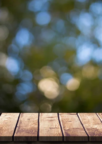 Houten tafel tegen wazig bladeren — Stockfoto