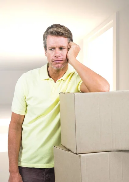 Sad man leaning on cardboard boxes against home — Stock Photo, Image