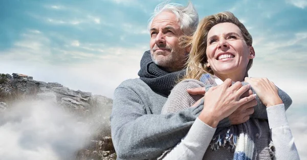 Couple en vêtements d'hiver contre les rochers et le ciel — Photo