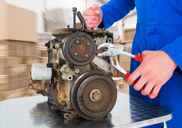 Mechanic working on machine against blurry boxes — Stock Photo, Image