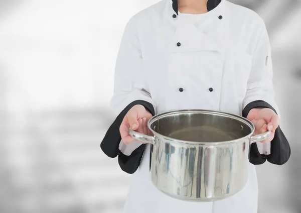 Chef with saucepan against blurry grey stairs — Stock Photo, Image