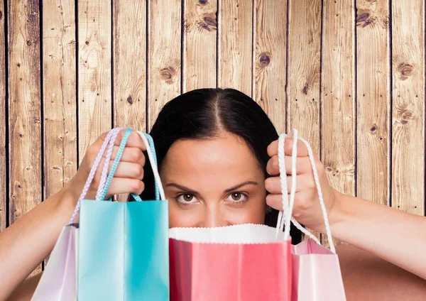 Femme avec sacs à provisions contre panneau de bois — Photo