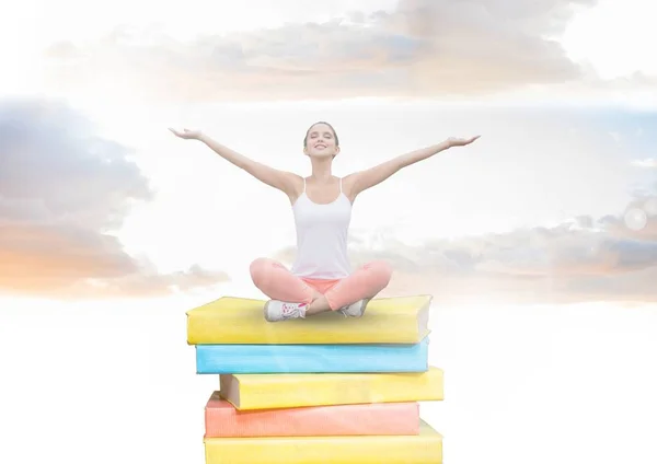 Chica meditando en libros apilados por la pared de ladrillo — Foto de Stock