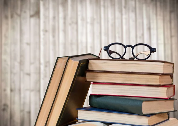 Pile of books and glasses against blurry wood panel — Stock Photo, Image