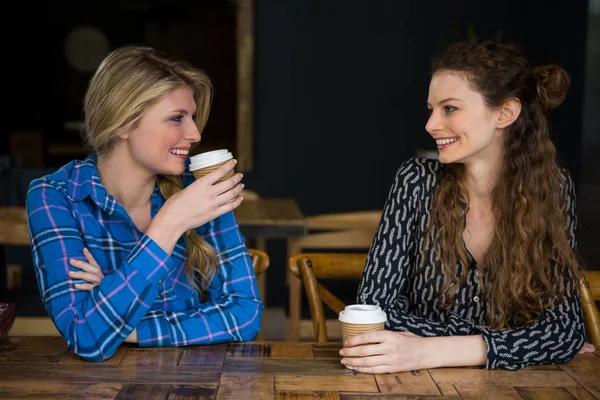 Amigos do sexo feminino tomar café enquanto conversa no café — Fotografia de Stock