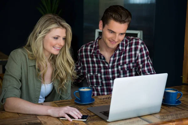 Couple using laptop at table in cafeteria — Stock Photo, Image